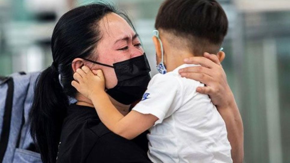 Une femme faisant ses adieux à un jeune enfant à l'aéroport de Hong Kong le 19 juillet 2021. © D.R